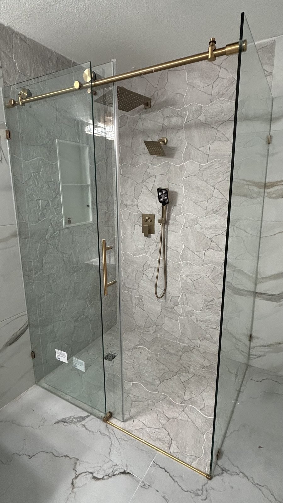 Frameless glass shower with brass fixtures